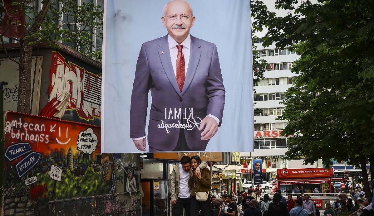 Ένα ζευγάρι περπατά κάτω από μια αφίσα του υποψήφιου Τούρκου προέδρου Κεμάλ Κιλιτσντάρογλου © EPA/SEDAT SUNA