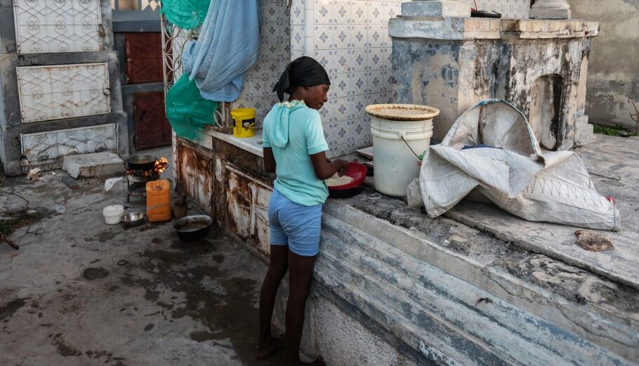 Στην Αϊτή μητέρα ετοιμάζει το φαγητό δίπλα σε τάφους στην πρωτεύουσα Πορτ-ο-Πρενς © EPA/Johnson Sabin