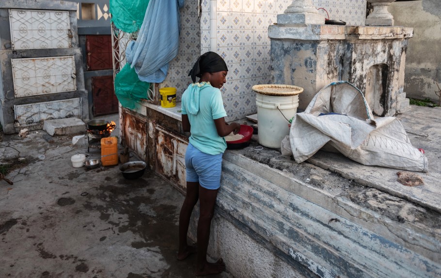Στην Αϊτή μητέρα ετοιμάζει το φαγητό δίπλα σε τάφους στην πρωτεύουσα Πορτ-ο-Πρενς © EPA/Johnson Sabin
