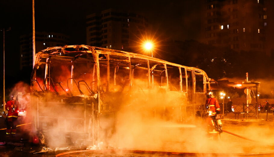 Πυροσβέστες σβήνουν λεωφορείο που κάηκε κατά τη διάρκεια συγκρούσεων μεταξύ διαδηλωτών και δυνάμεων των ΜΑΤ στη Ναντέρ, κοντά στο Παρίσι @ EPA/MOHAMMED BADRA