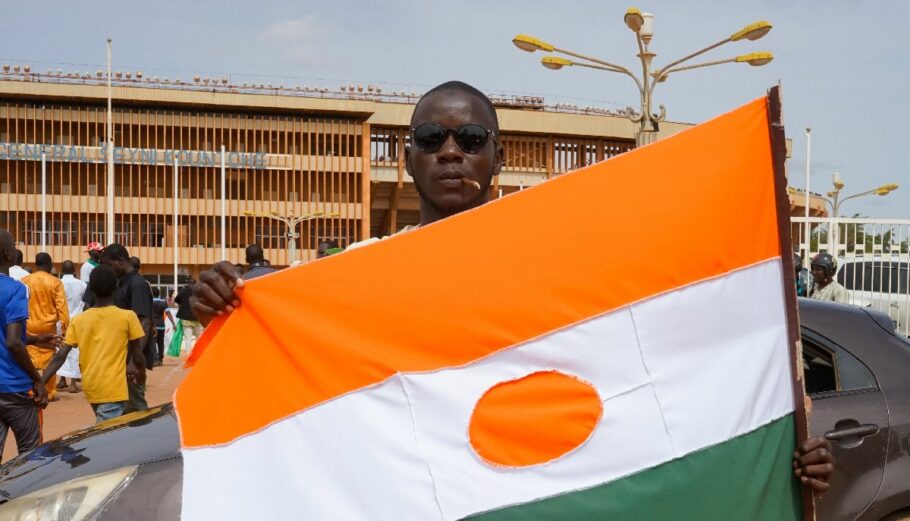 Άνδρας με σημαία του Νίγηρα πηγαίνει σε συγκέντρωση για να δείξει την υποστήριξή τους στο στρατιωτικό πραξικόπημα © EPA/ISSIFOU DJIBO