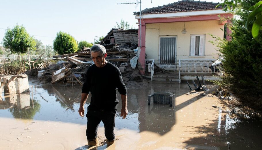 Κάτοικος στο χωριό Σωτήριο Λάρισας περπατά στην καλυμμένη από λάσπη αυλή του, μετά τις καταστροφικές πλημμύρες που προκάλεσε η κακοκαιρία Daniel © ΑΠΕ-ΜΠΕ/ΝΙΚΟΣ ΧΑΤΖΗΠΟΛΙΤΗΣ